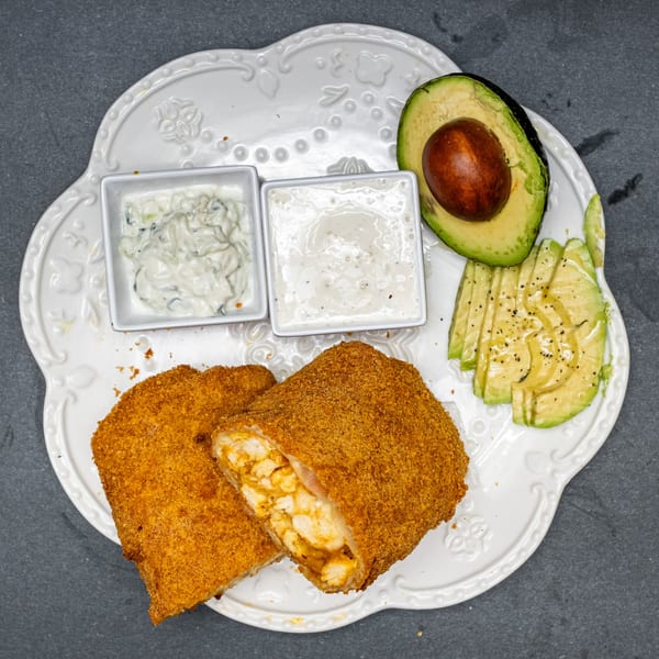 Crispy fried chicken rolls with dipping sauces and sliced avocado on a white plate.